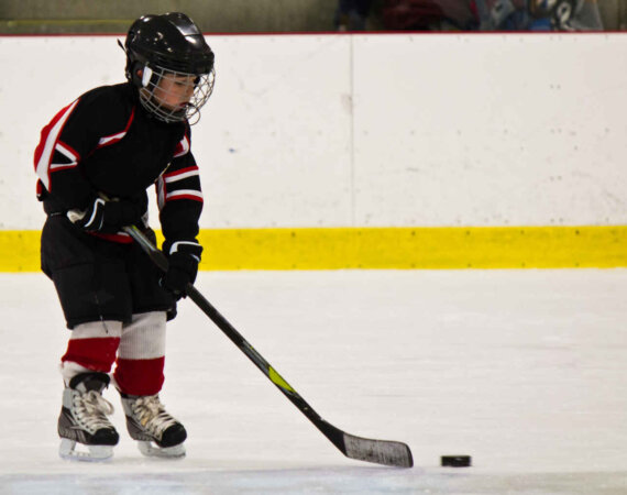 Child Skating And Playing Hockey In An Arena