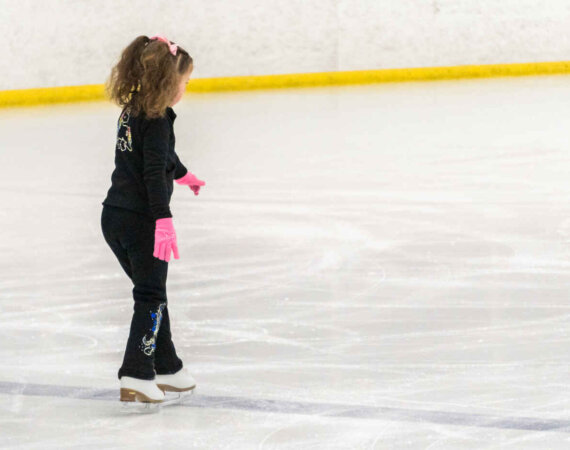 Little Girl Practicing Figure Skating Moves On The Indoor Ice Ri