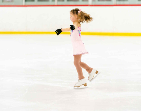 Little Girl Practicing Figure Skating On An Indoor Ice Skating R